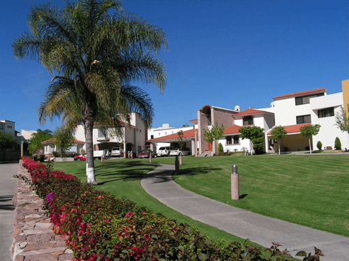 Entrada principal de Villantigua con pilares de piedra y vegetación
